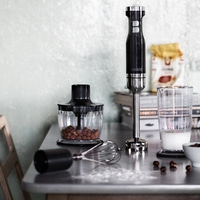 Ustensiles de cuisine sur une table : mixeur, récipient, lait, noix, fouet et ingrédients.