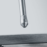 Metal pipe with nozzle pointing at a series of metal plates, close up