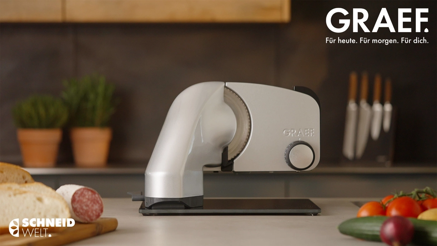 Affettatrice GRAEF con pane, salame e verdure in cucina.