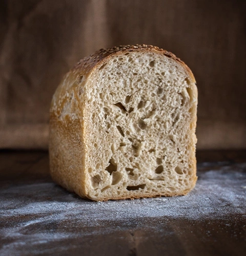 A loaf of bread on a wooden surface with flour, close-up shot.