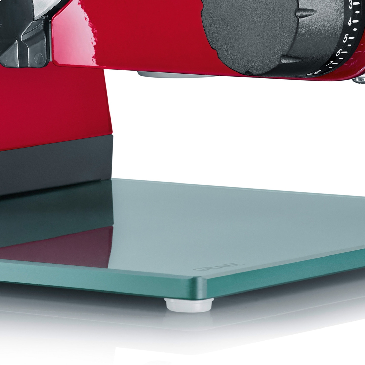 Gros plan d'une trancheuse à viande rouge avec plateau en verre et cadran de réglage.