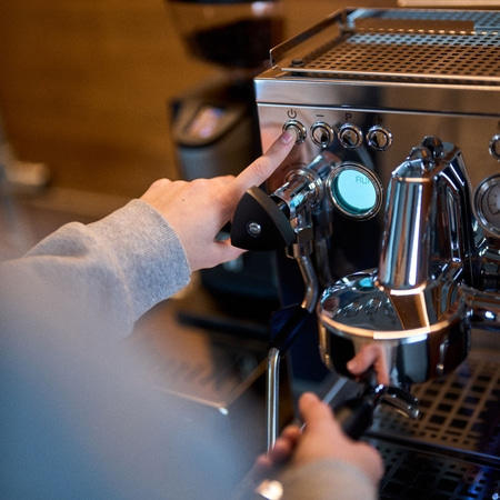 Person pressing button on coffee machine, close-up, hands, device, stainless steel