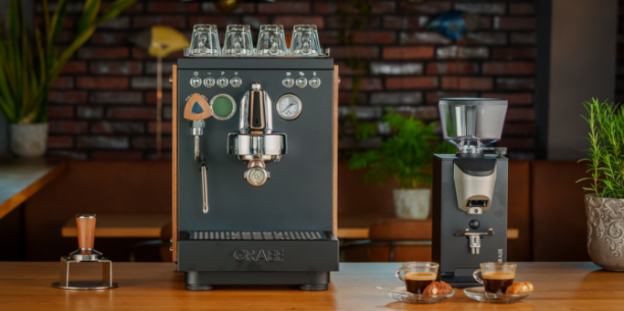Espresso machine and coffee grinder with two cups of espresso on a wooden table.