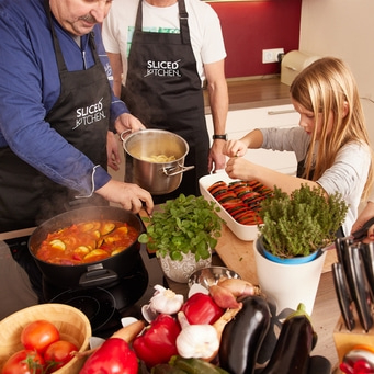 Famiglia che cucina insieme in cucina, verdure e utensili da cucina.