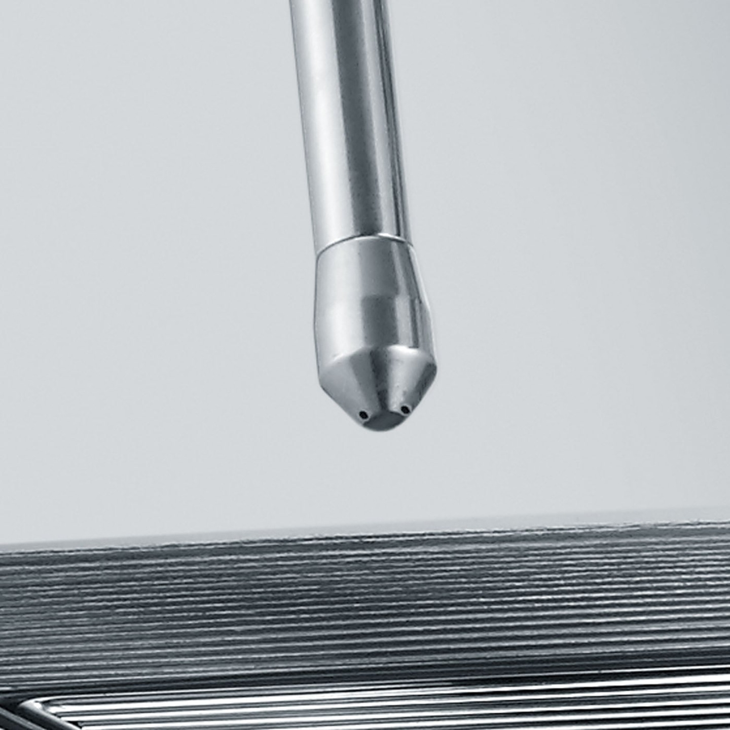 Metal pipe with nozzle pointing at a series of metal plates, close up