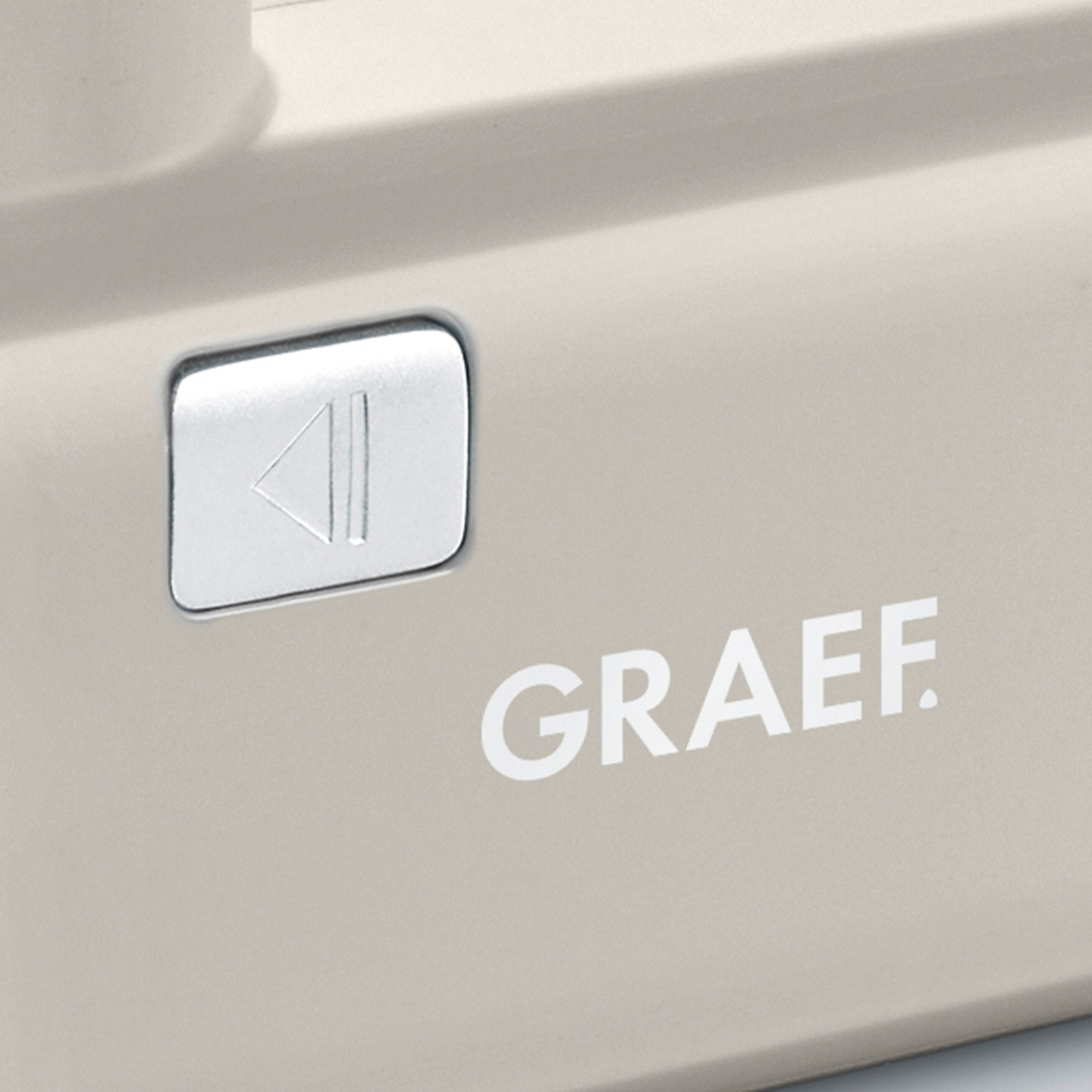 Graef appliance with play button and logo. Beige color, close-up detail.