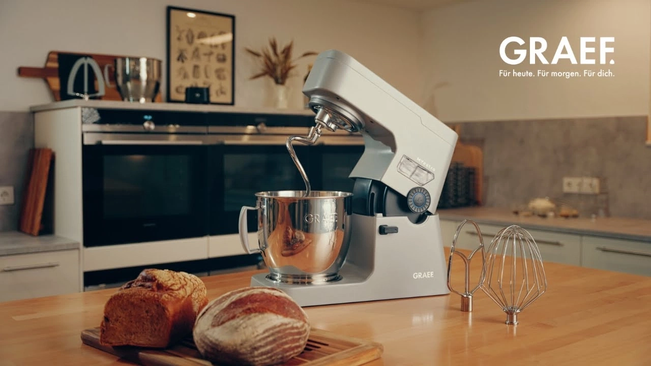Impastatrice Graef con pane e accessori su tavolo di legno.