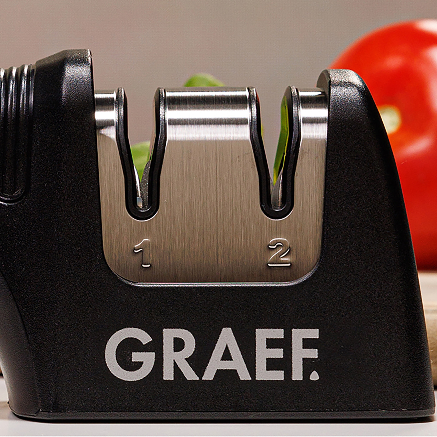 Un affilacoltelli Graef con i numeri 1 e 2, accanto a un pomodoro rosso.