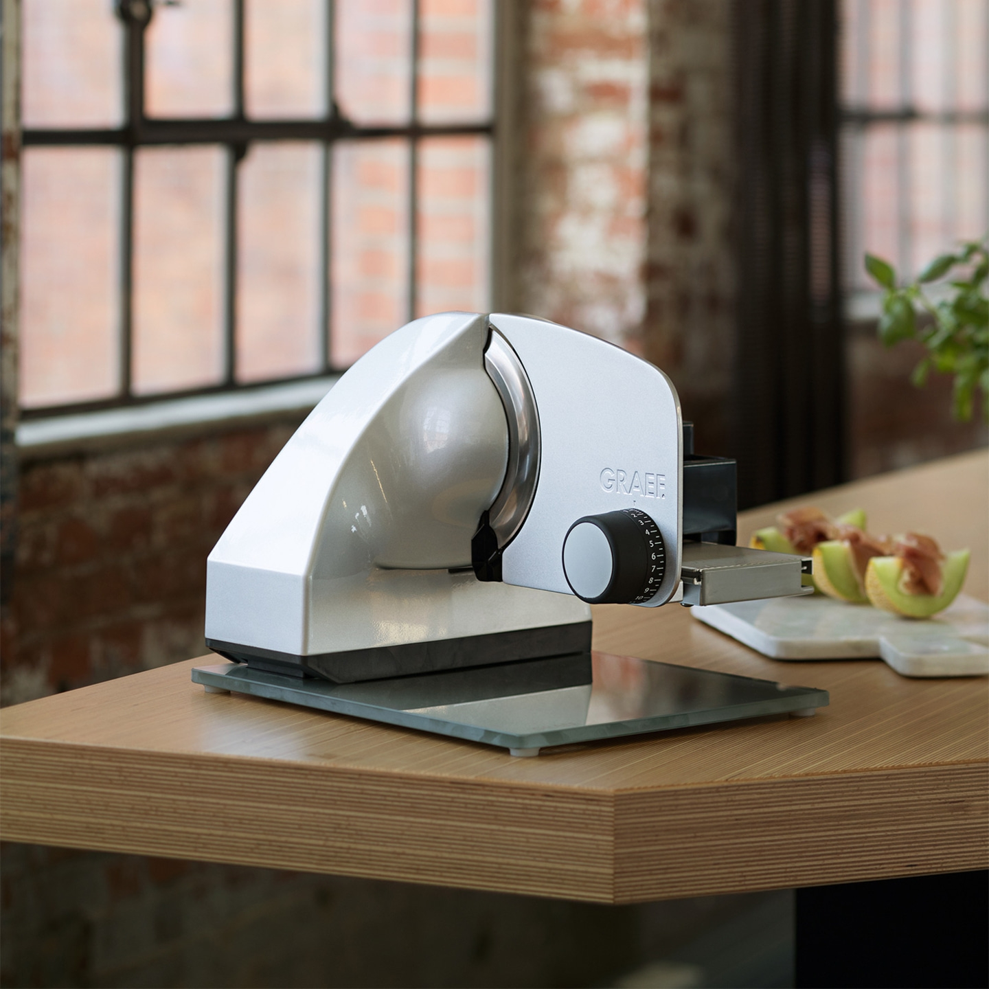 Une trancheuse Graef argentée sur une table en bois avec des tranches de melon.