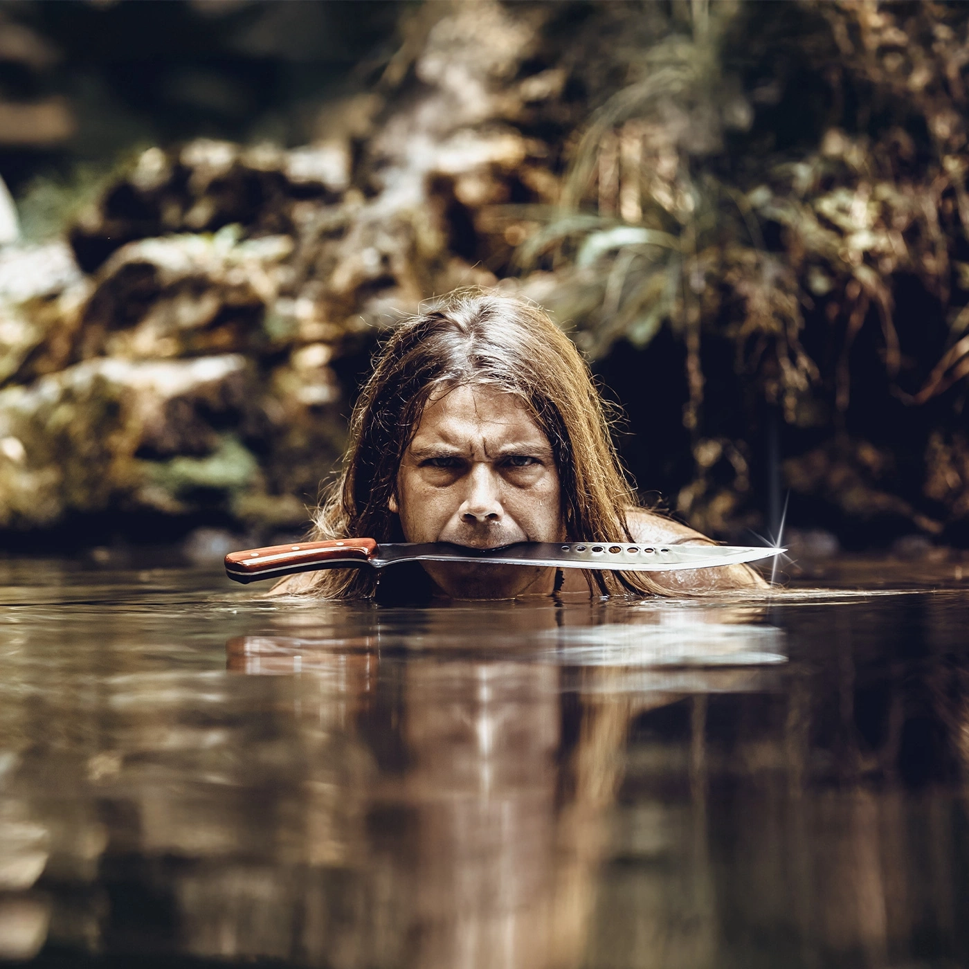 Homme avec couteau dans la bouche dans l'eau