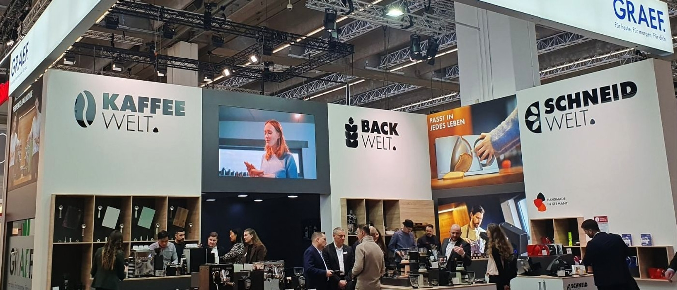 Stand del mondo del caffè e della panificazione con persone e loghi.