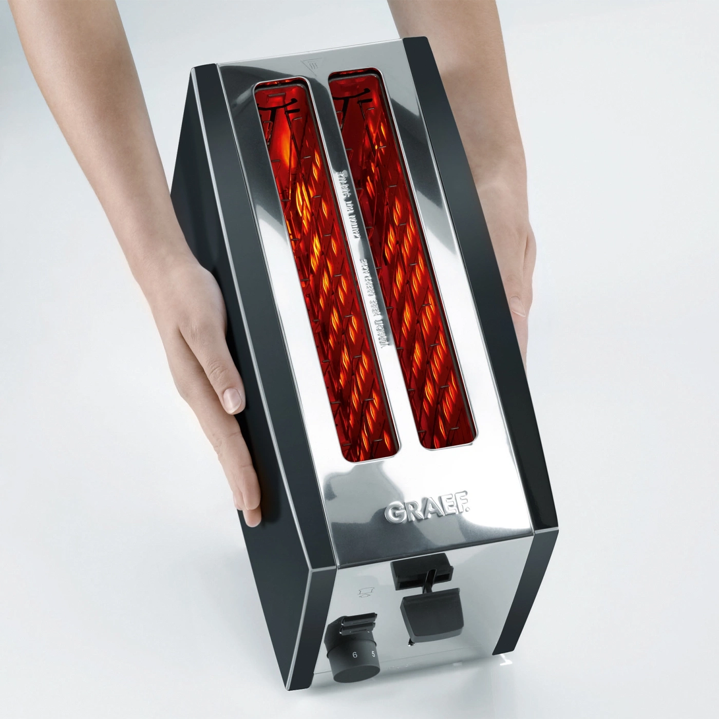 Hands holding a toaster with glowing heating elements, brand GRAEF visible.