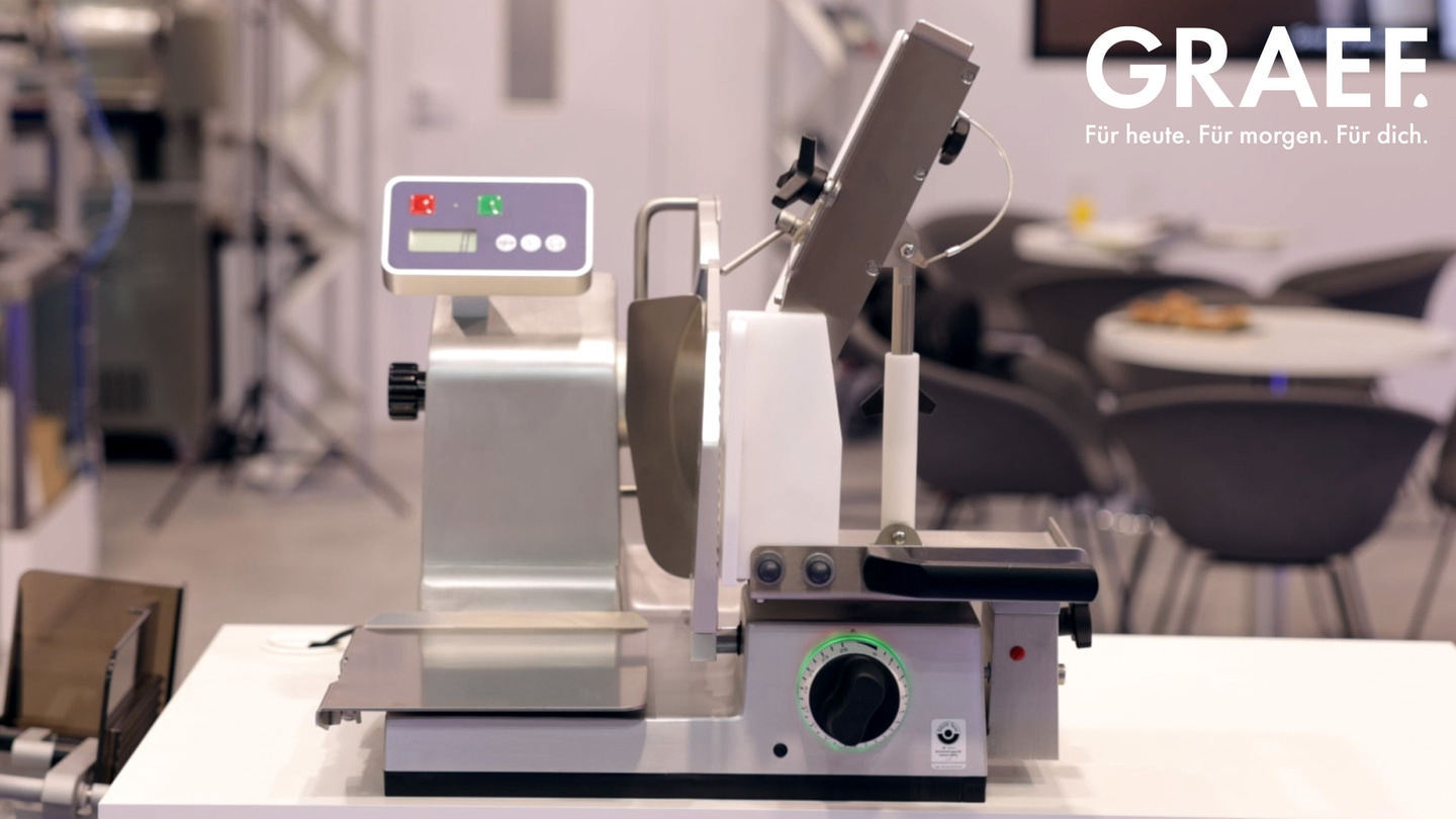 Affettatrice su un tavolo, logo GRAEF sullo sfondo, design moderno.