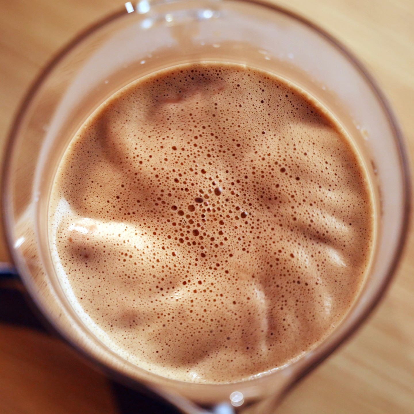 Gros plan de chocolat chaud mousseux dans un verre.