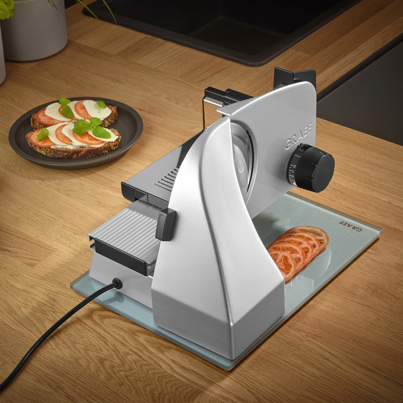 Graef slicer with tomato slices and bread on a wooden surface