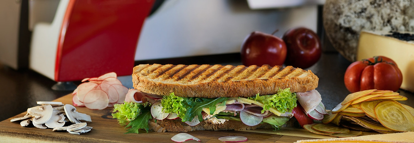 Delicious sandwich with vegetables and fruits on a wooden board