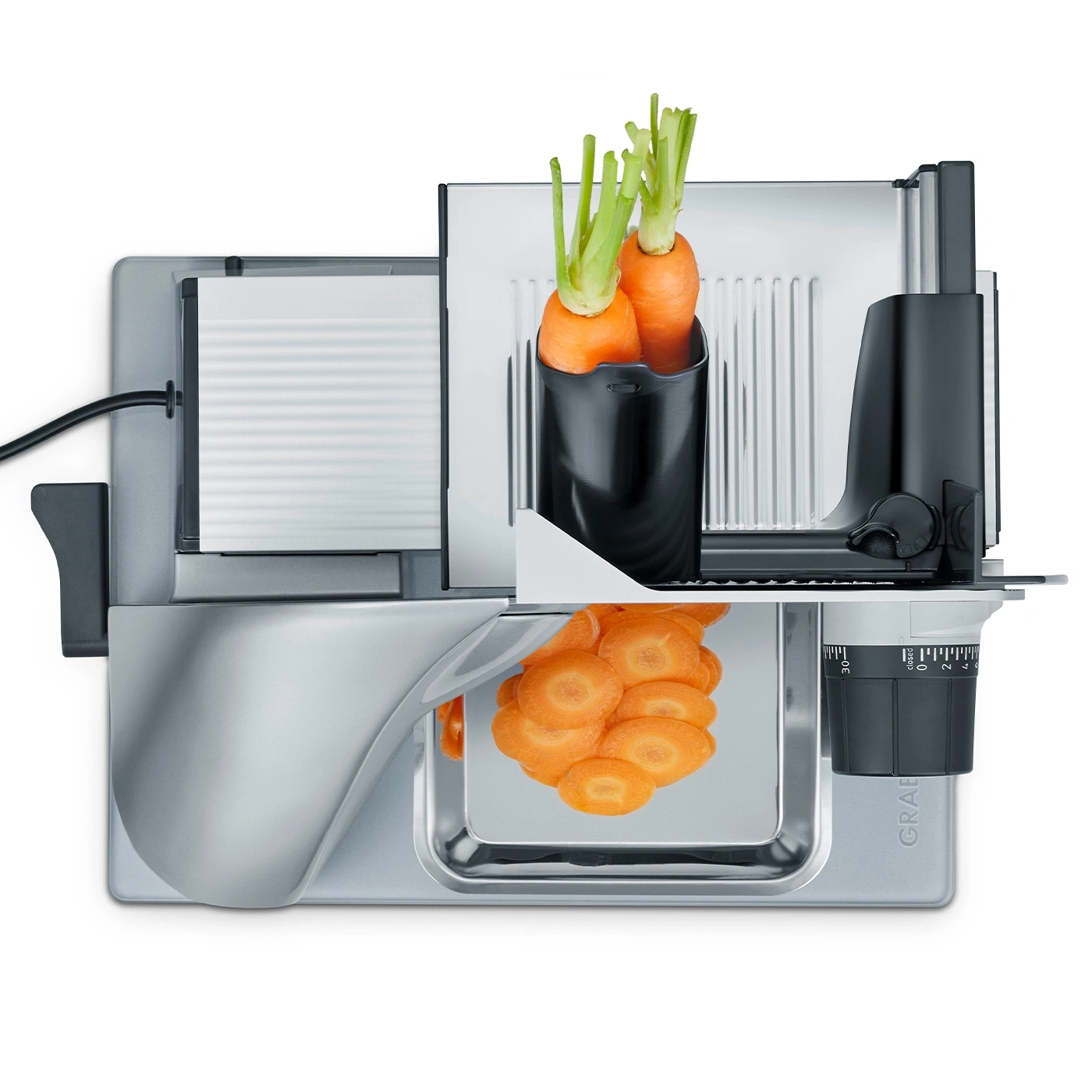 Affettatrice di verdure con carote e fette, acciaio inossidabile, primo piano, isolato