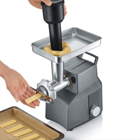 Cookie machine with dough, hands, and baking sheet. Gray machine, cookies being made.