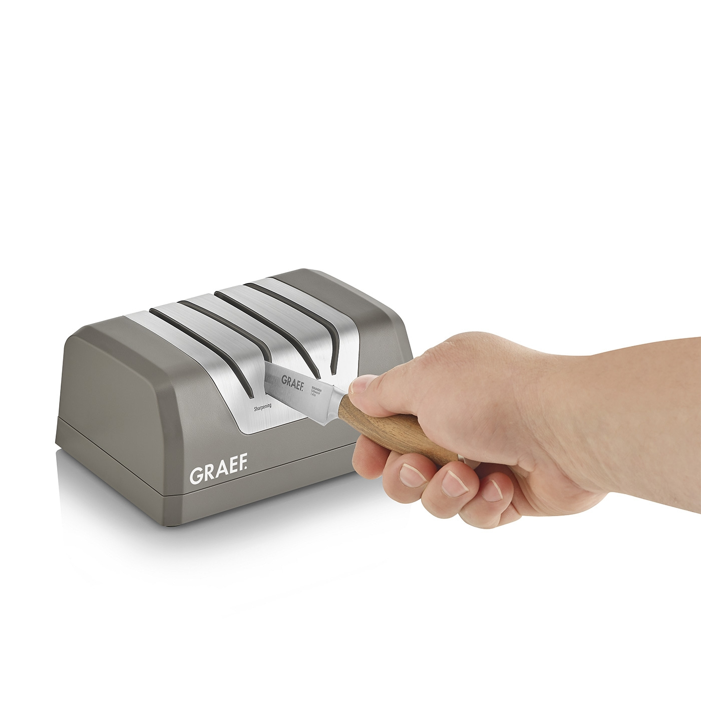 Sharpening a knife with a GRAEF sharpener. Gray sharpener and knife in hand.