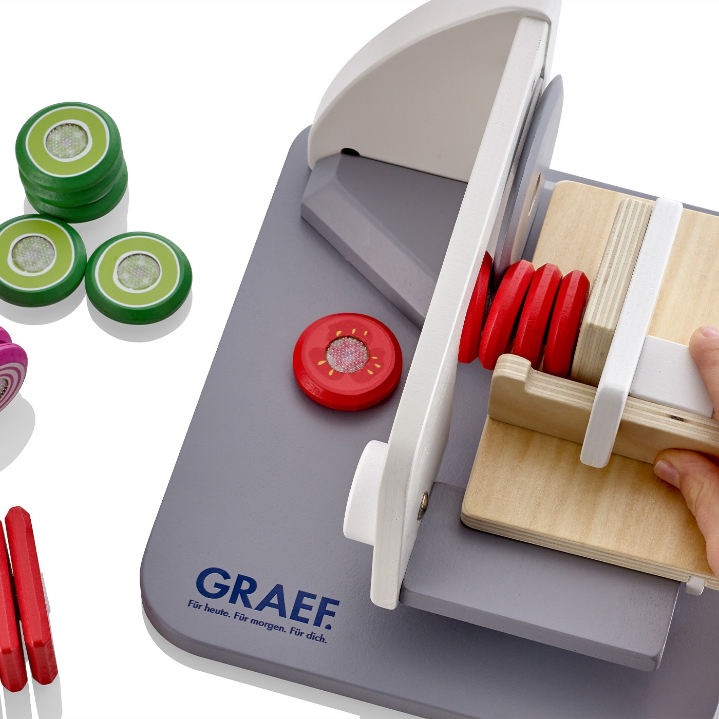 Toy vegetable slicer with wooden vegetables and GRAEF logo on gray board