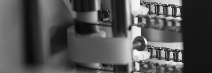 Primo piano di una catena metallica e di un pezzo di macchina in bianco e nero.