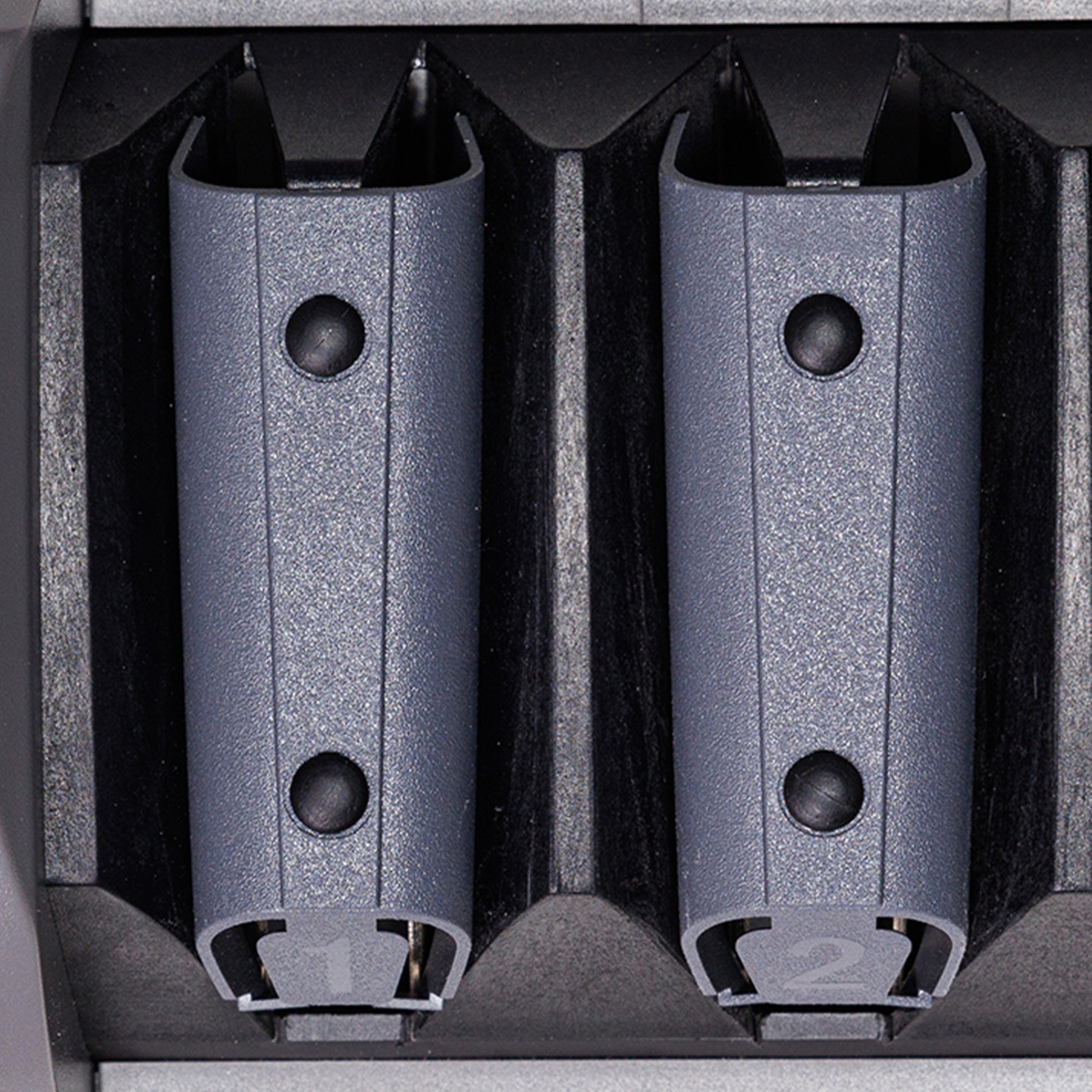 Due portabatterie grigi in un caricabatterie nero.