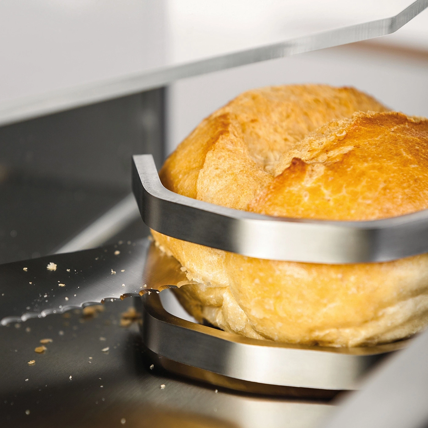 Close-up of a bread roll being sliced with a bread slicer, kitchen detail