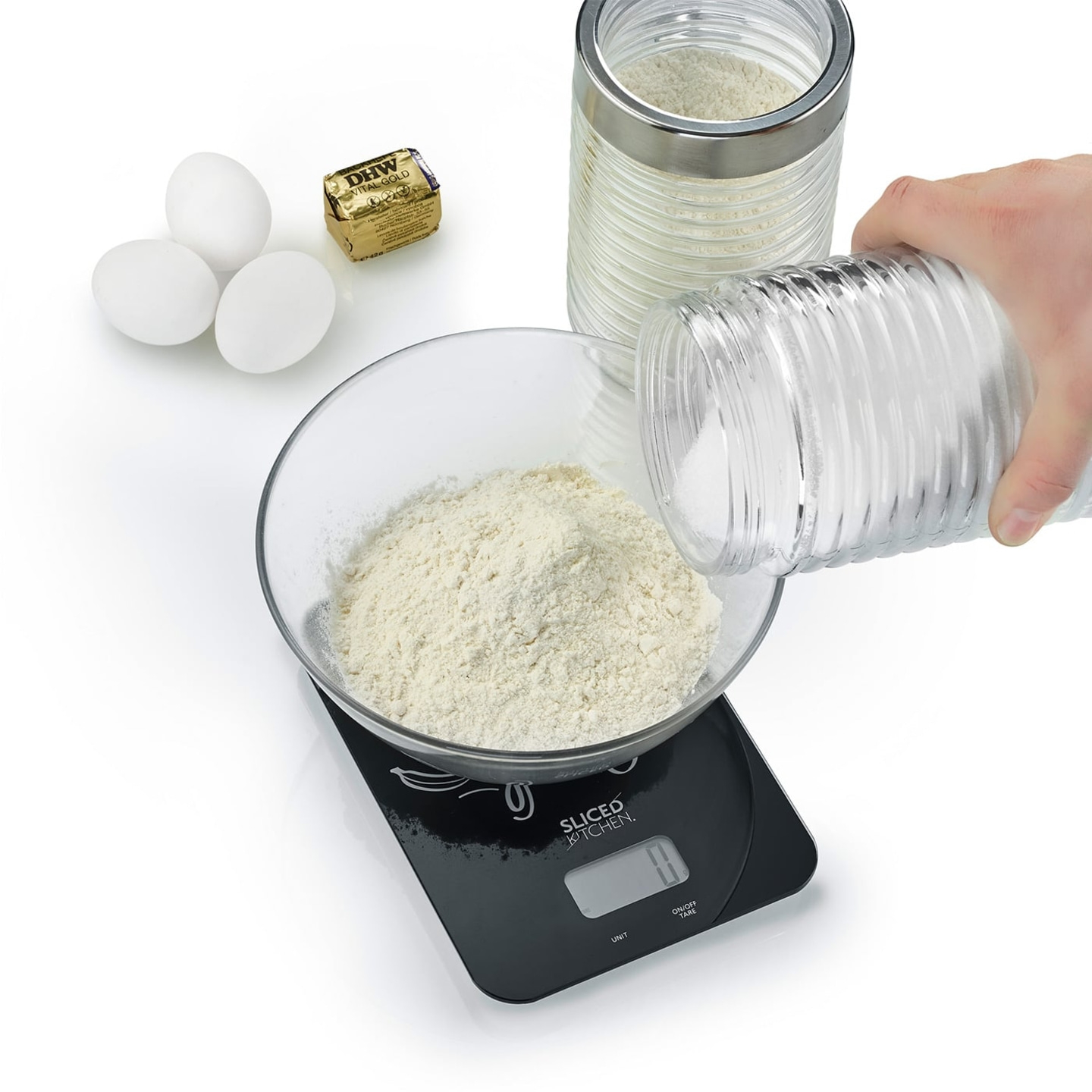 Baking ingredients: eggs, butter, flour, sugar, scale, glass bowl, hand pouring.