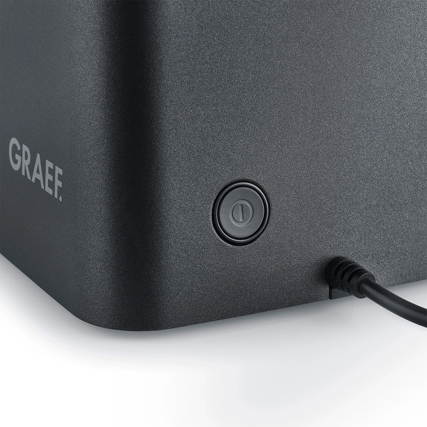 Close-up of a Graef appliance with a button and cable on a white background
