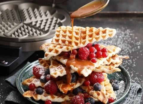 Waffle con frutti di bosco e salsa al caramello servite su un piatto, deliziose.