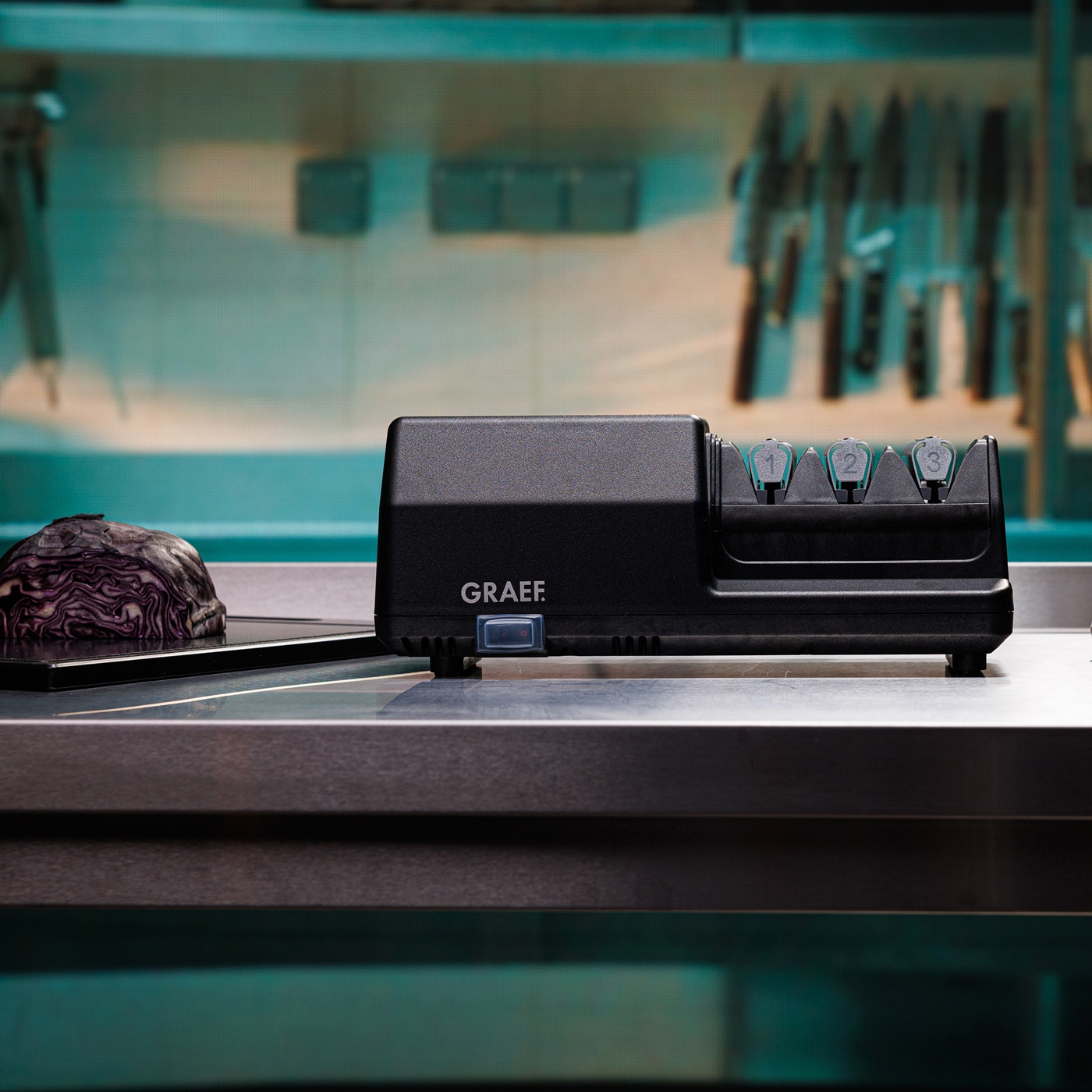 Affilacoltelli nero con verdure su una superficie metallica in cucina.