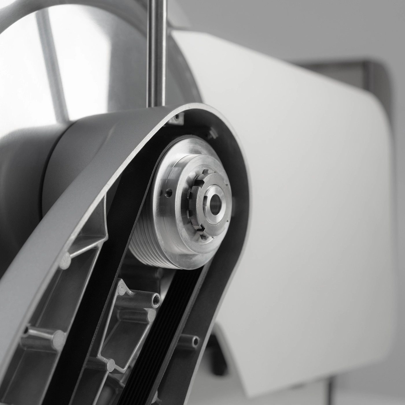 Primo piano di un dispositivo meccanico con cinghie e ingranaggi, in scala di grigi
