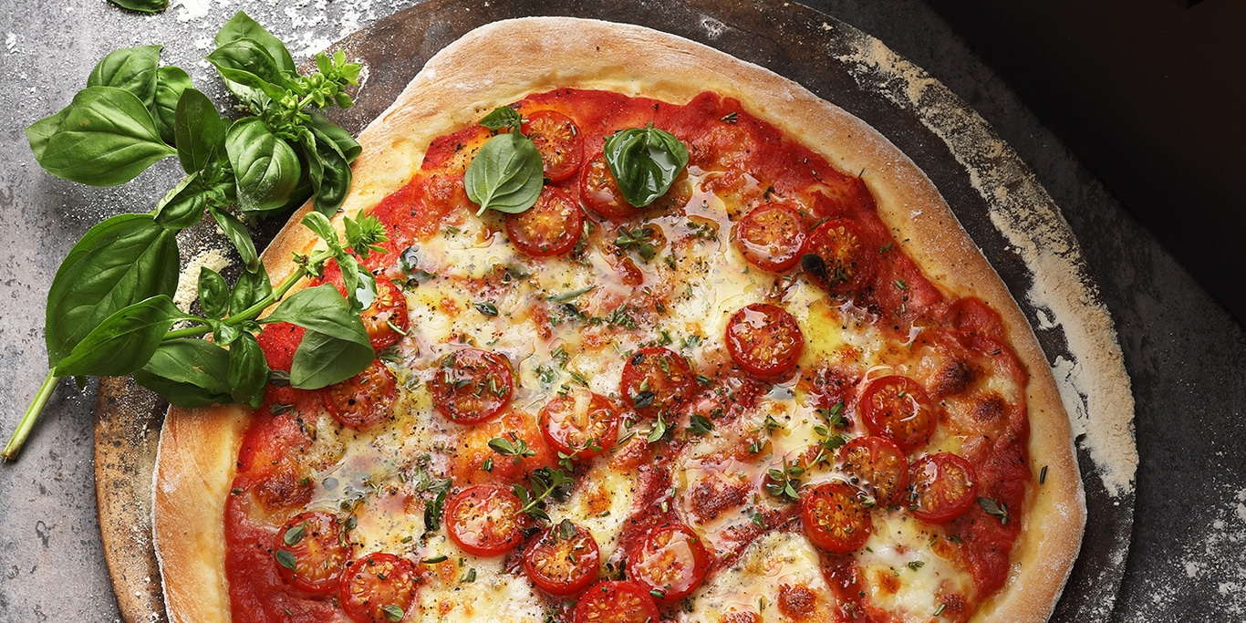 Pizza aux tomates et au basilic sur une planche de bois