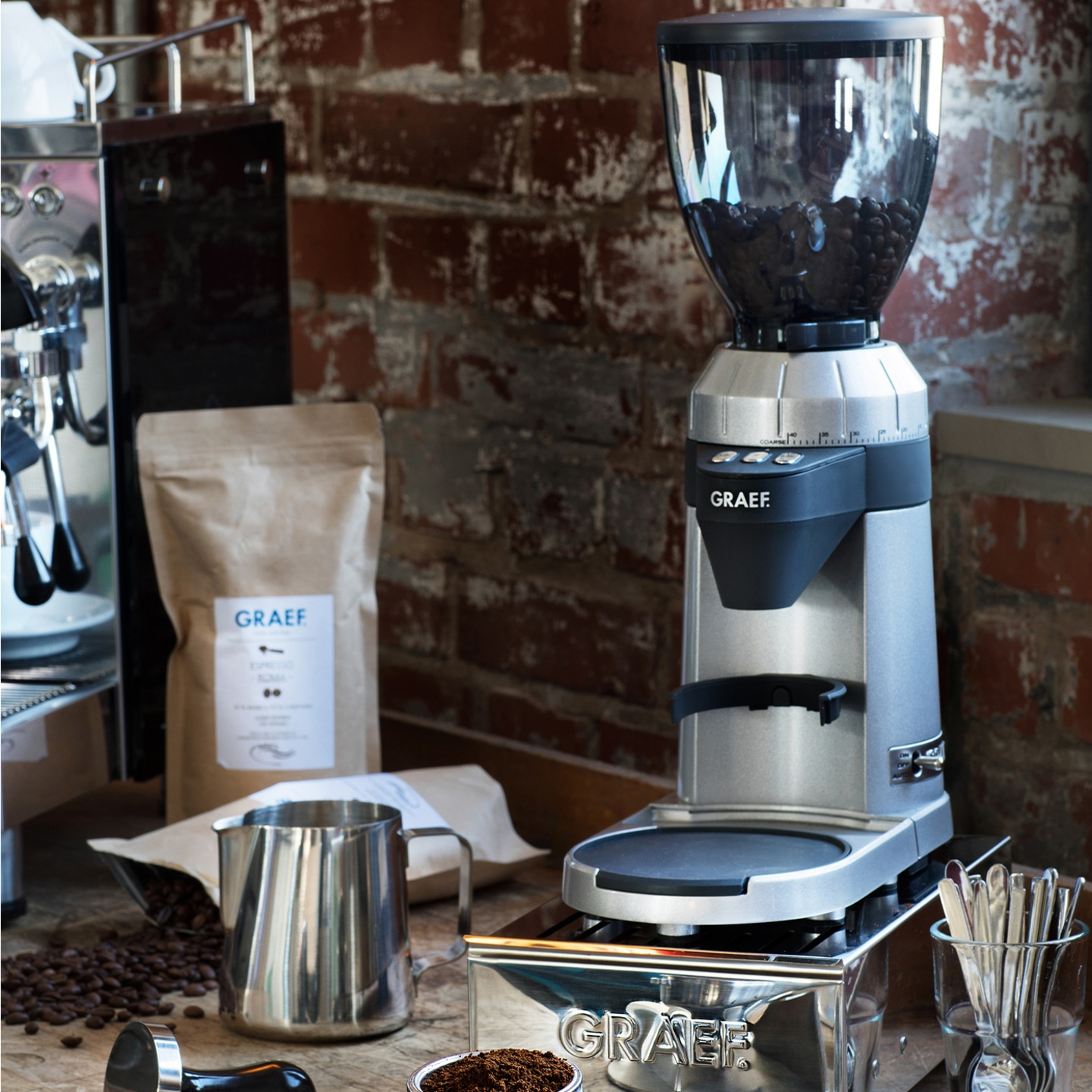 Moulin à café avec grains, accessoires et logo GRAEF sur la table.