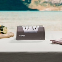 Graef knife sharpener on table with vegetables and sea in the background