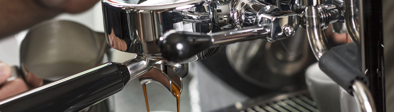Primo piano di una macchina per caffè espresso che versa caffè in una tazza, metallo lucido.