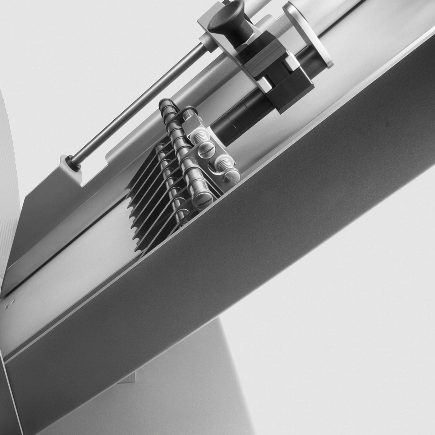 Close-up of a metal food slicer with details and shadows, angled view
