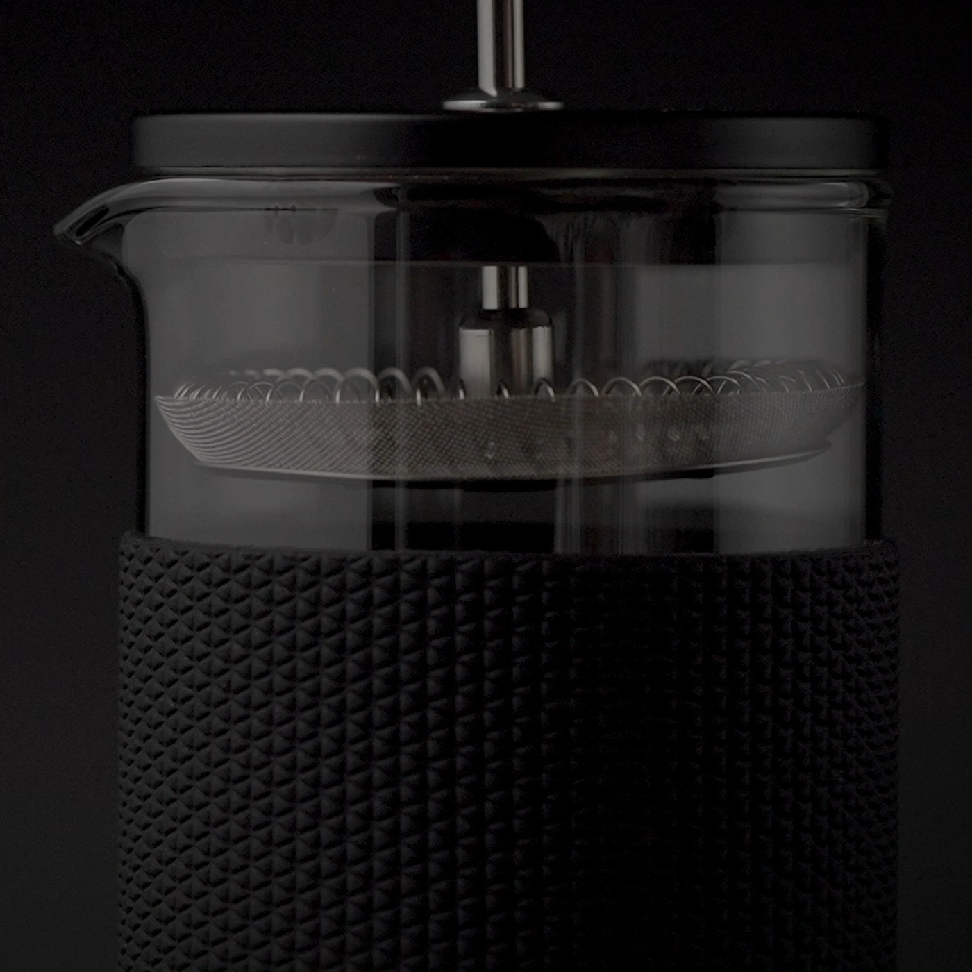 Gros plan d'une cafetière à piston noire avec carafe en verre et filtre métallique.