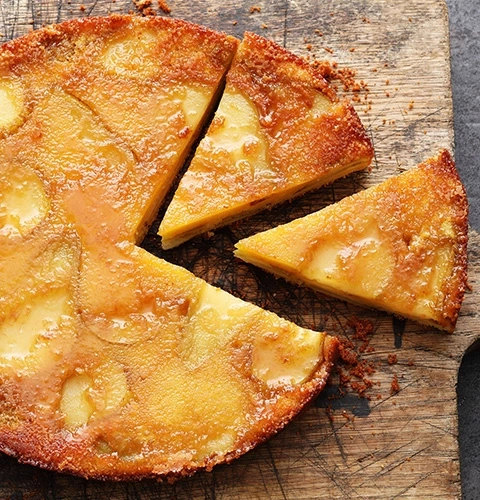 Un délicieux gâteau aux pommes servi sur une planche de bois, coupé en tranches.