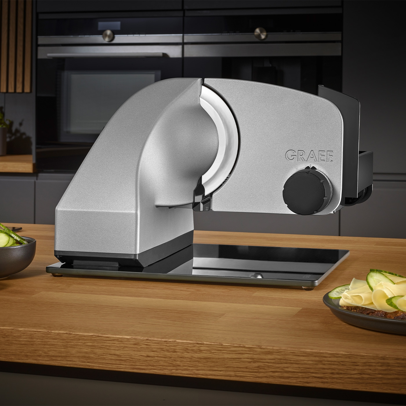 Graef slicer on wooden table with food and kitchen appliances in the background