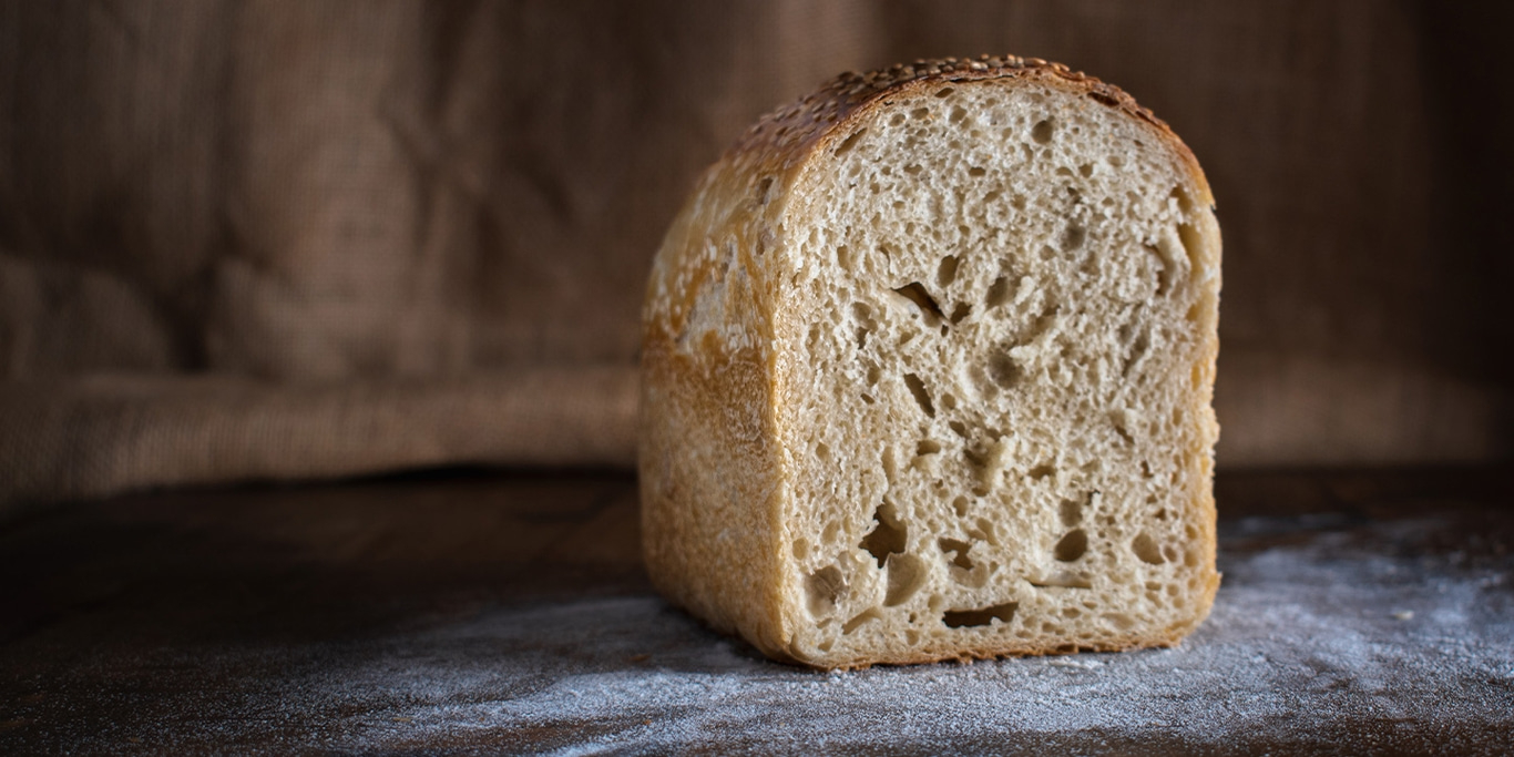 Un pain, saupoudré de farine, posé sur une surface en bois.