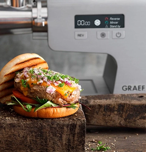 Hamburger con formaggio e cipolle davanti a tritacarne