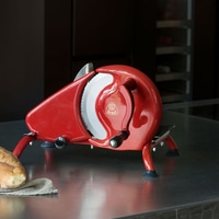 Red slicer with bread on a dark surface, kitchen appliance.