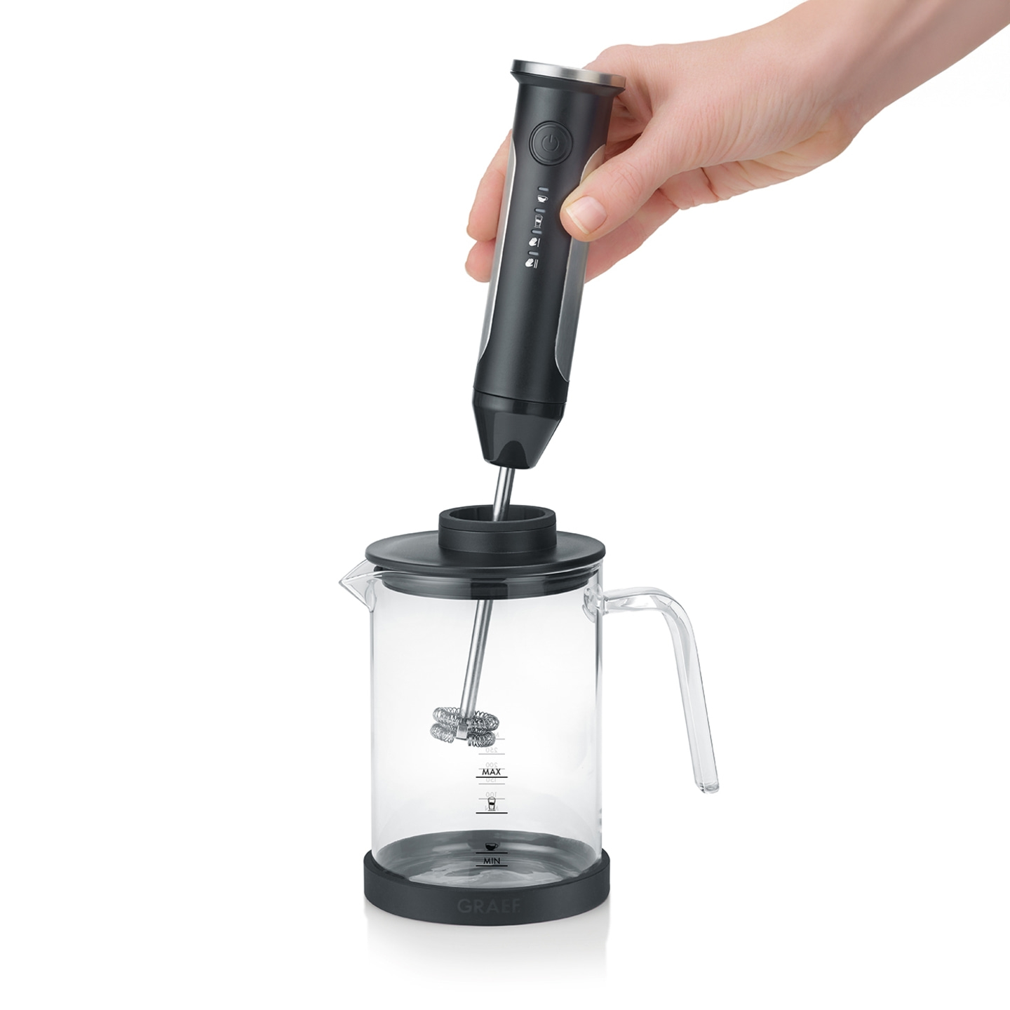 Hand holding a milk frother above a glass container, ready for coffee preparation