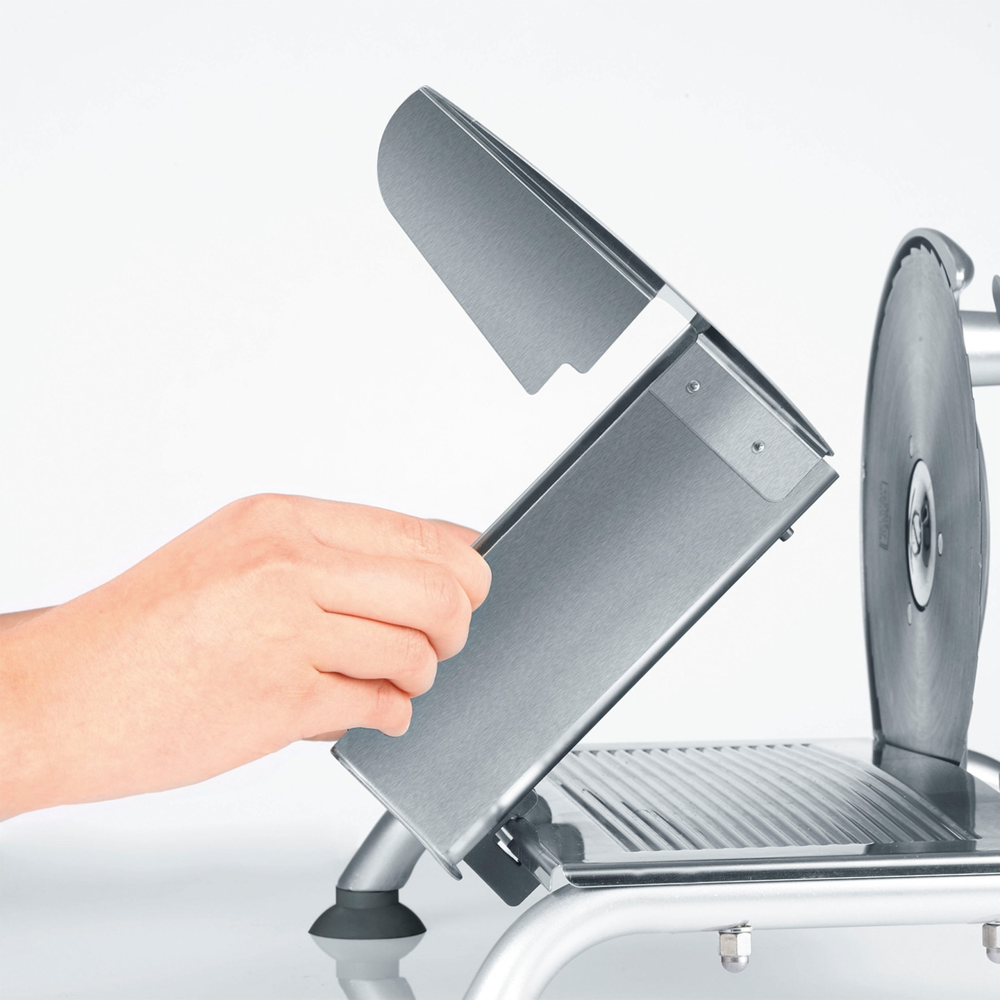 Gros plan d'une trancheuse à viande avec protection ouverte et main