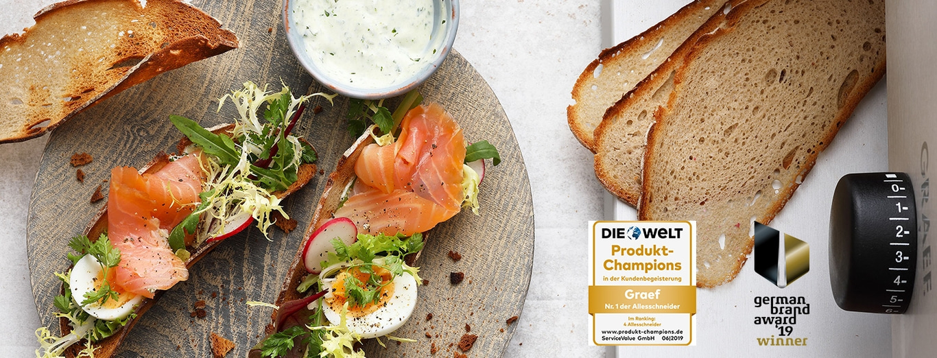 Toasted bread with salmon, egg, and salad, served with sauce and awards.