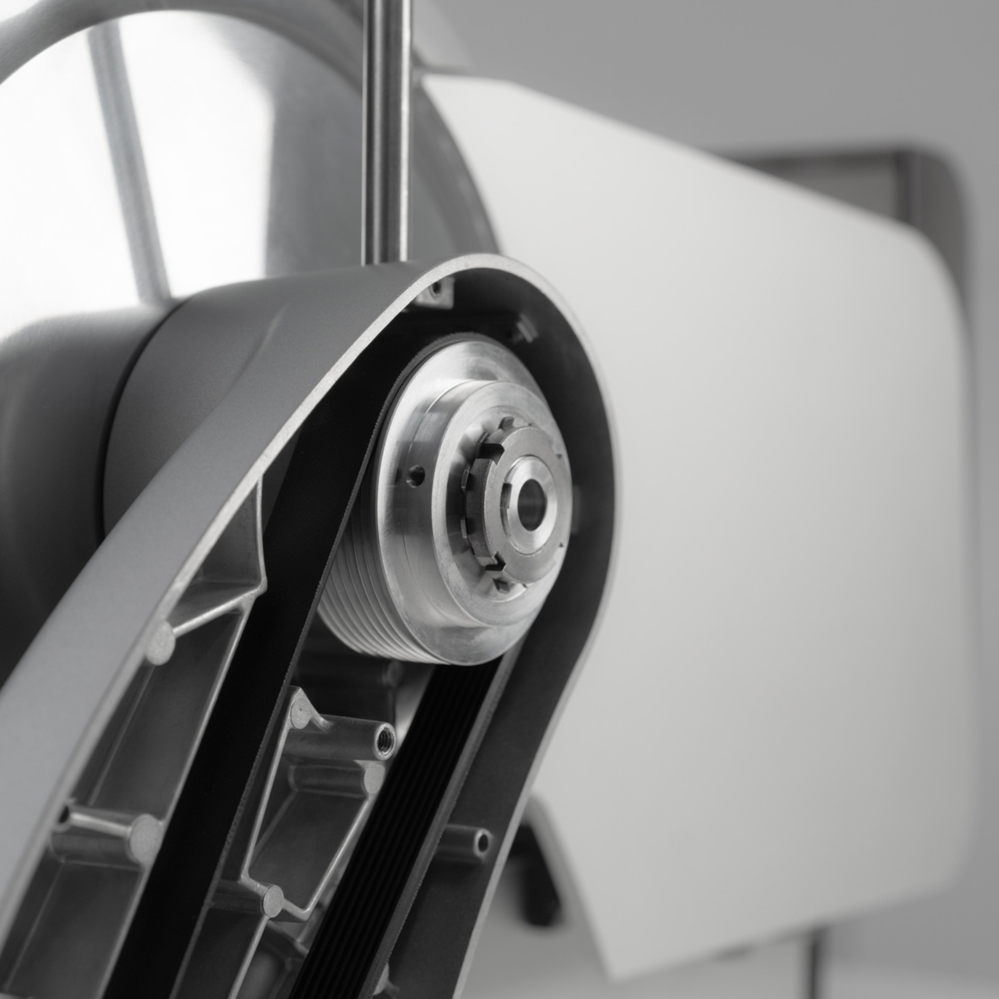 Primo piano di un dispositivo meccanico con cinghie e ingranaggi, in scala di grigi