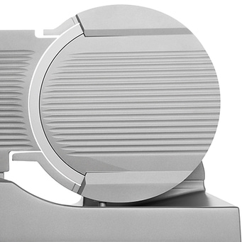 Close-up of a silver meat slicer with a ridged blade and detailed design