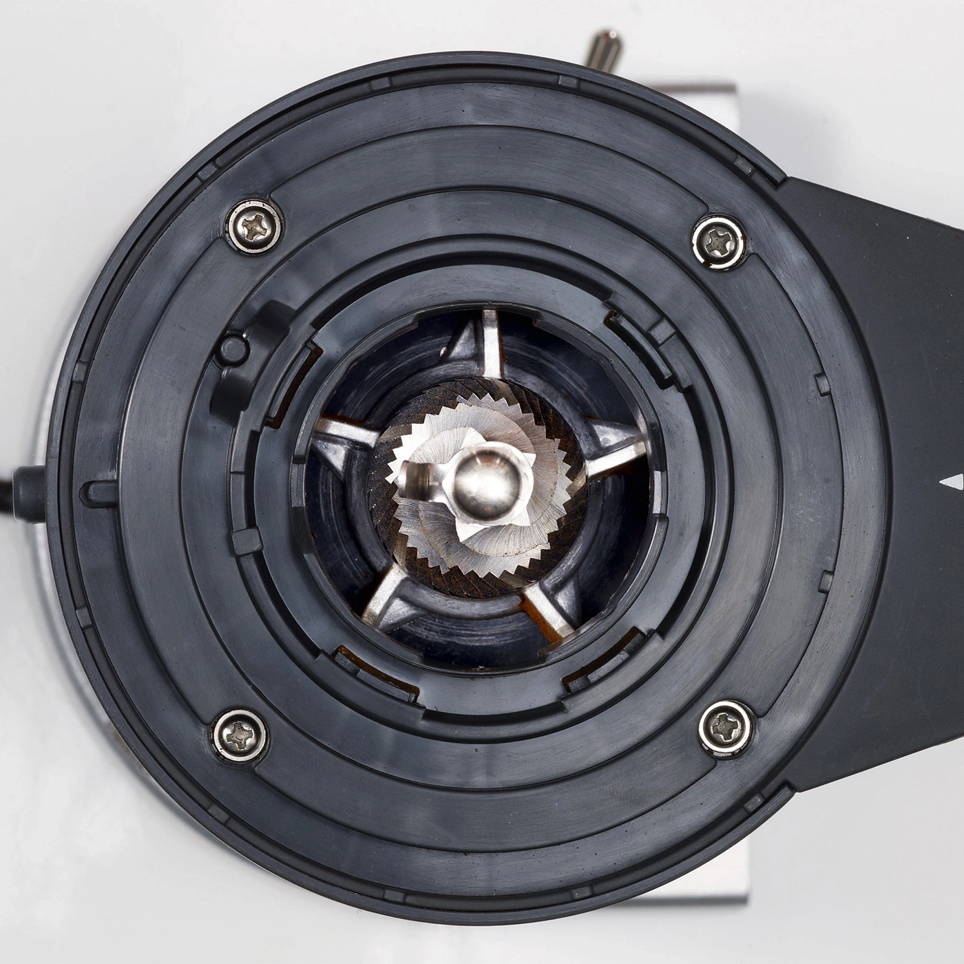 Close-up of the top of a coffee grinder showing the burrs and screws.