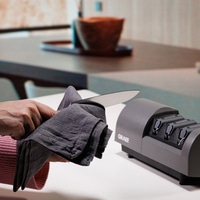 Coltello pulito con un panno accanto ad un affilacoltelli.